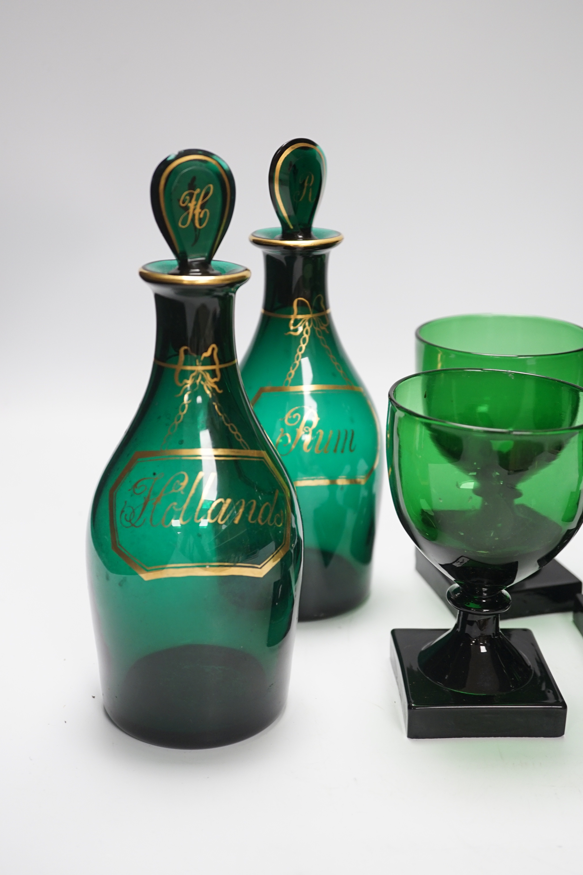 A pair of small Bristol green decanters, Rum and Hollands, c.1800 and five 19th century green glass rummers, with lemon squeezer bases, decanters 22cm high